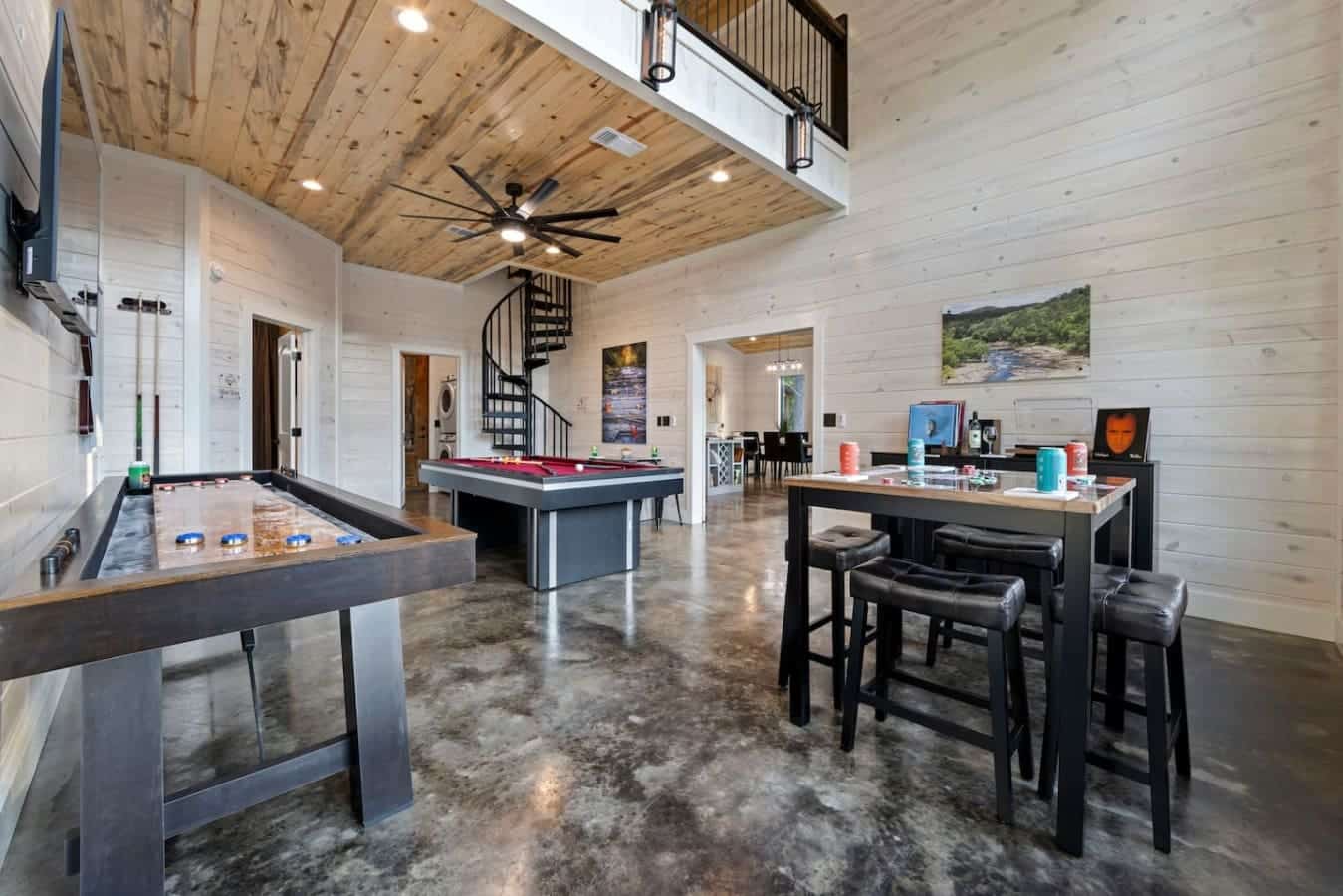 Now that’s a game room done right! From shuffleboard to pool to poker, it's the ultimate indoor hangout—complete with a spiral staircase and rustic vibes. Let the games begin!