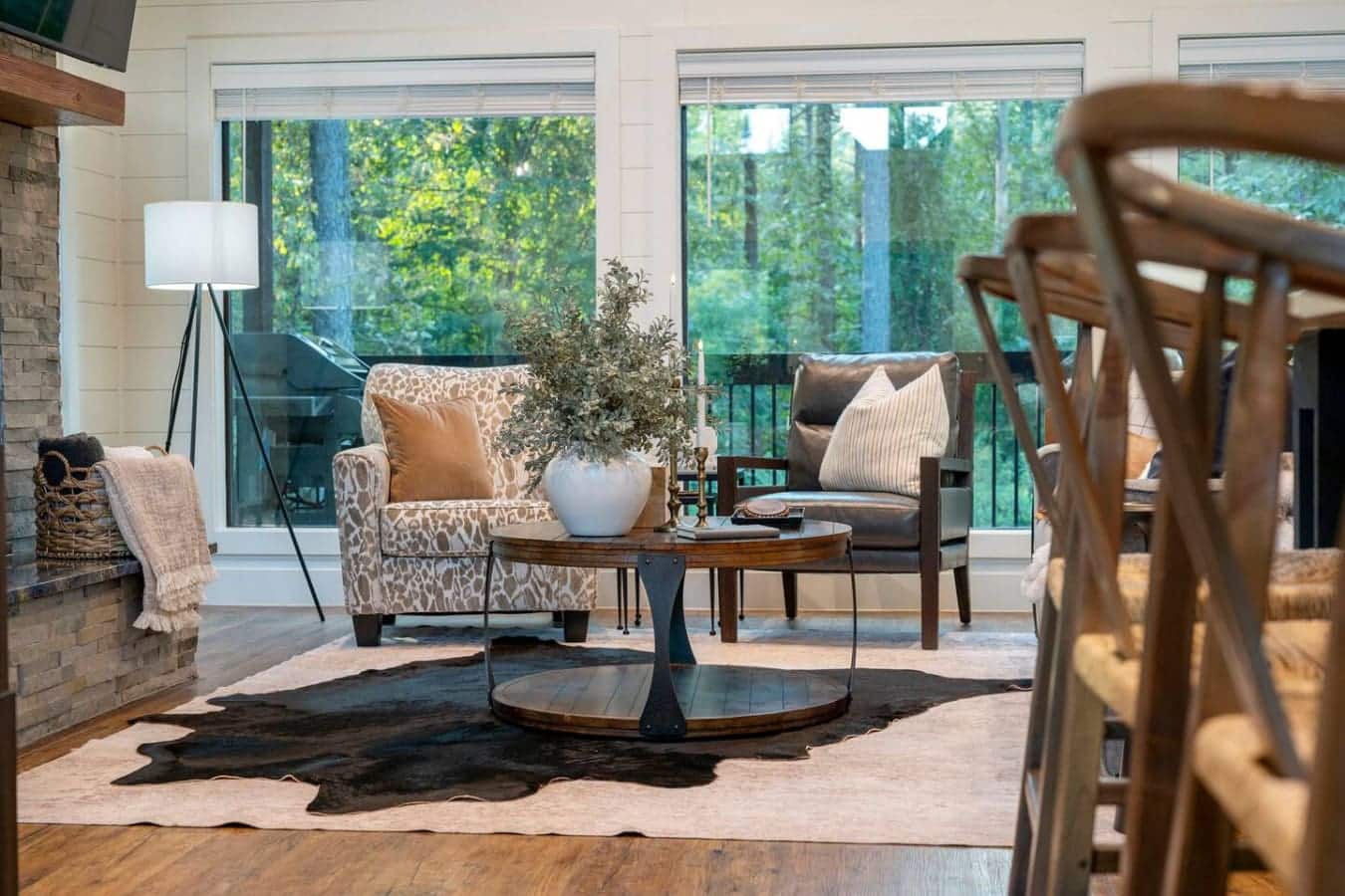 The whole vibe of this room—floor-to-ceiling windows, natural light everywhere, and just enough seating to hang out without feeling cramped—makes it impossible not to just sink into a chair and lose track of time staring out at the trees.