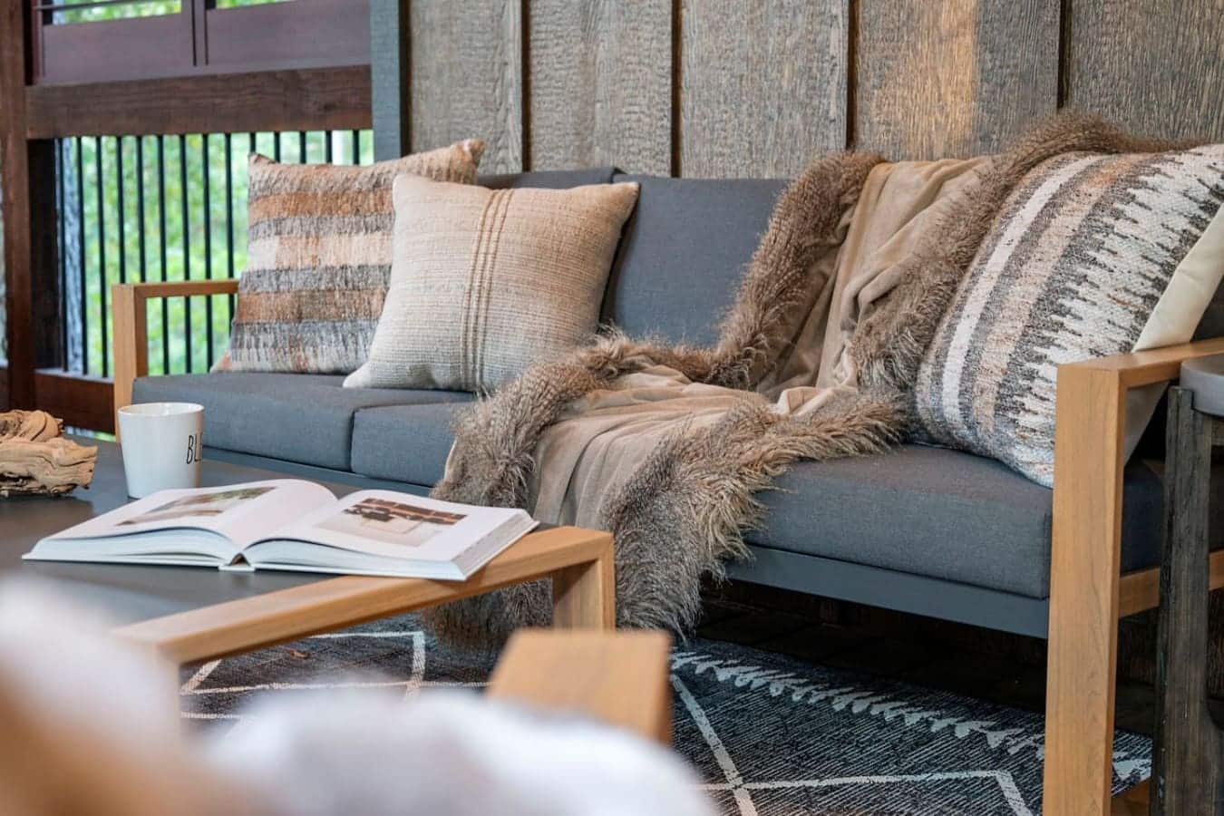 This living room setup is basically the definition of hygge—just throw some blankets and pillows on that gray sofa, curl up with a book, and let those textured wood walls and natural light turn an afternoon into the kind of day you never want to leave.