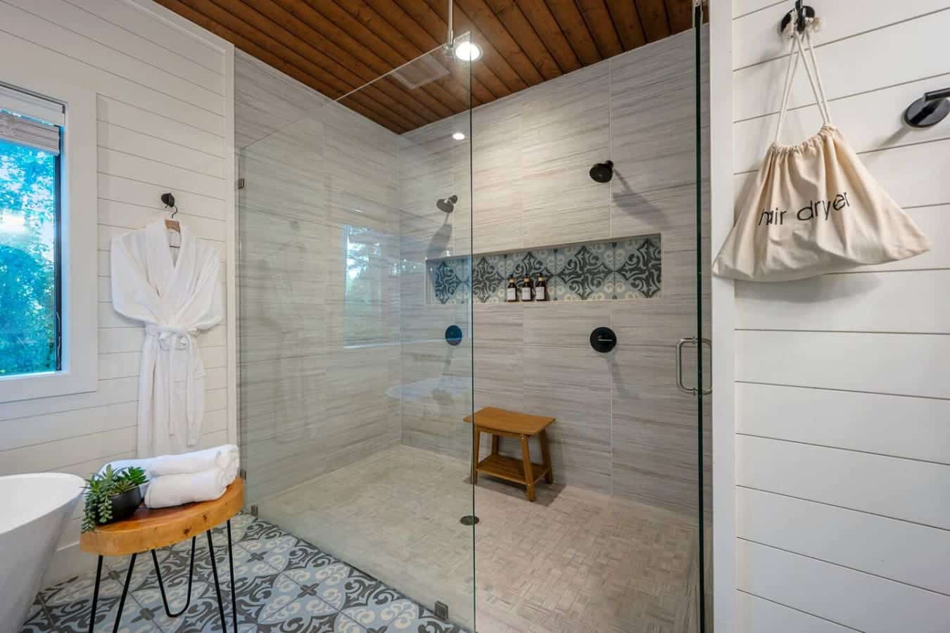 This spa-like shower setup with the dual heads, that gorgeous geometric tile detail, and a wooden bench to sit on while you soak in the moment is basically the kind of place that makes you understand why people actually look forward to shower time.