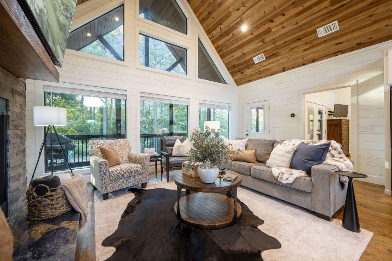 This living room with those floor-to-ceiling windows, the wood-beamed ceiling, and that perfect mix of cozy seating basically feels like someone designed the ultimate space for just sitting around, talking, and actually enjoying being together.
