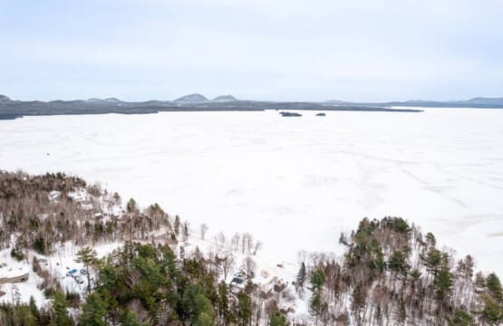 Imagine waking up to this—a pristine frozen lake stretching out in front of you with mountains in the distance and your own slice of Maine wilderness right outside your door.