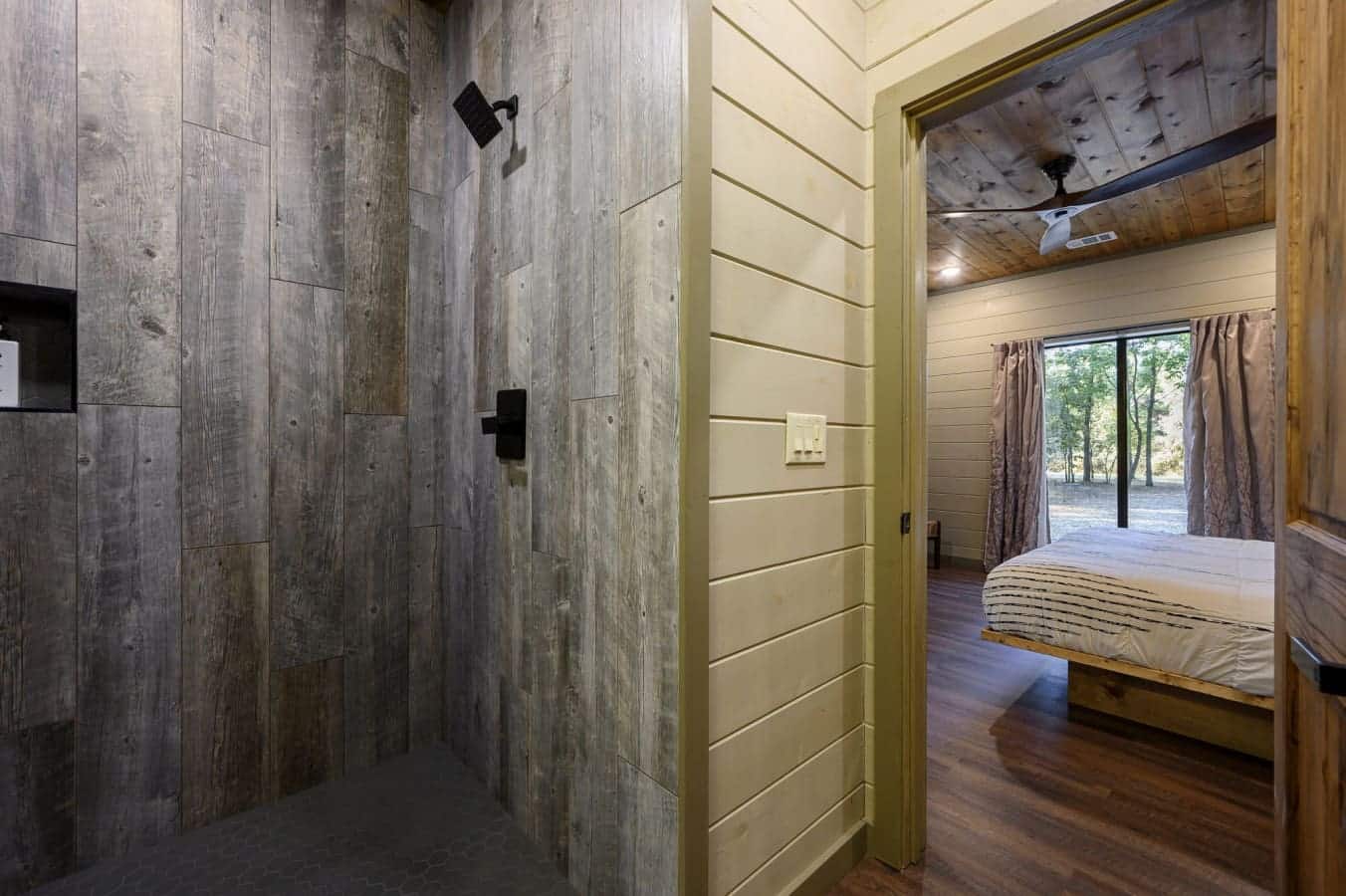 Warm wood accents and large windows create a cozy atmosphere in this bedroom.