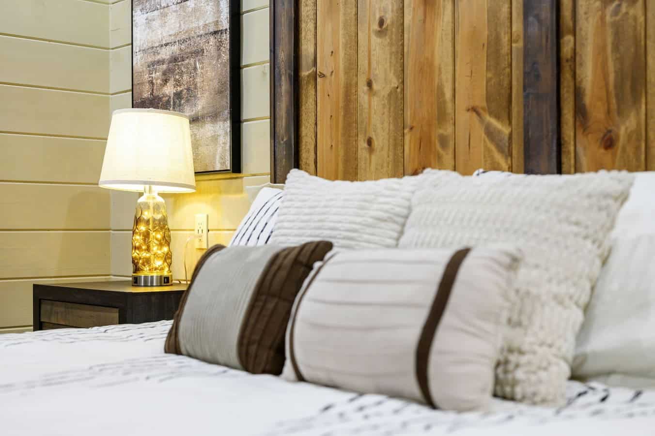 Close-up detail of the cozy bedding and warm lighting in the primary bedroom.