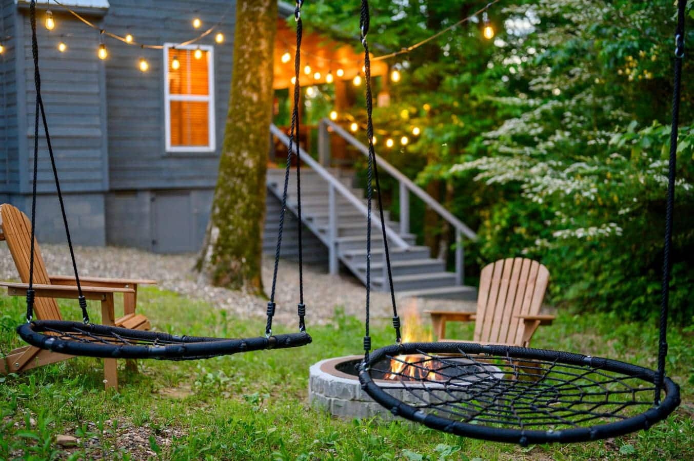 Two circular net swings are suspended from trees, creating a relaxing seating area.