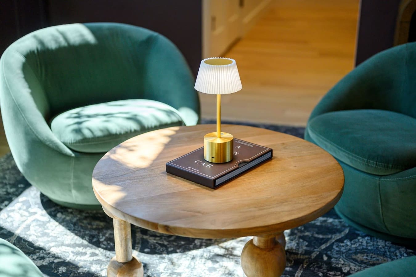 This cozy conversation nook with those plush teal chairs, a sleek brass table lamp, and a wooden side table basically looks like the perfect spot to curl up with a book or have a long chat while sunlight streams in from somewhere nearby.