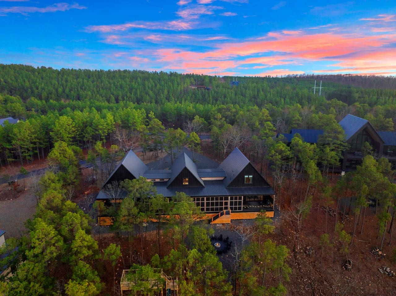 This stunning modern home nestled deep in the pines with those dramatic peaked roofs and glowing windows basically looks like the kind of forest escape where you could completely disconnect from the chaos and just breathe.
