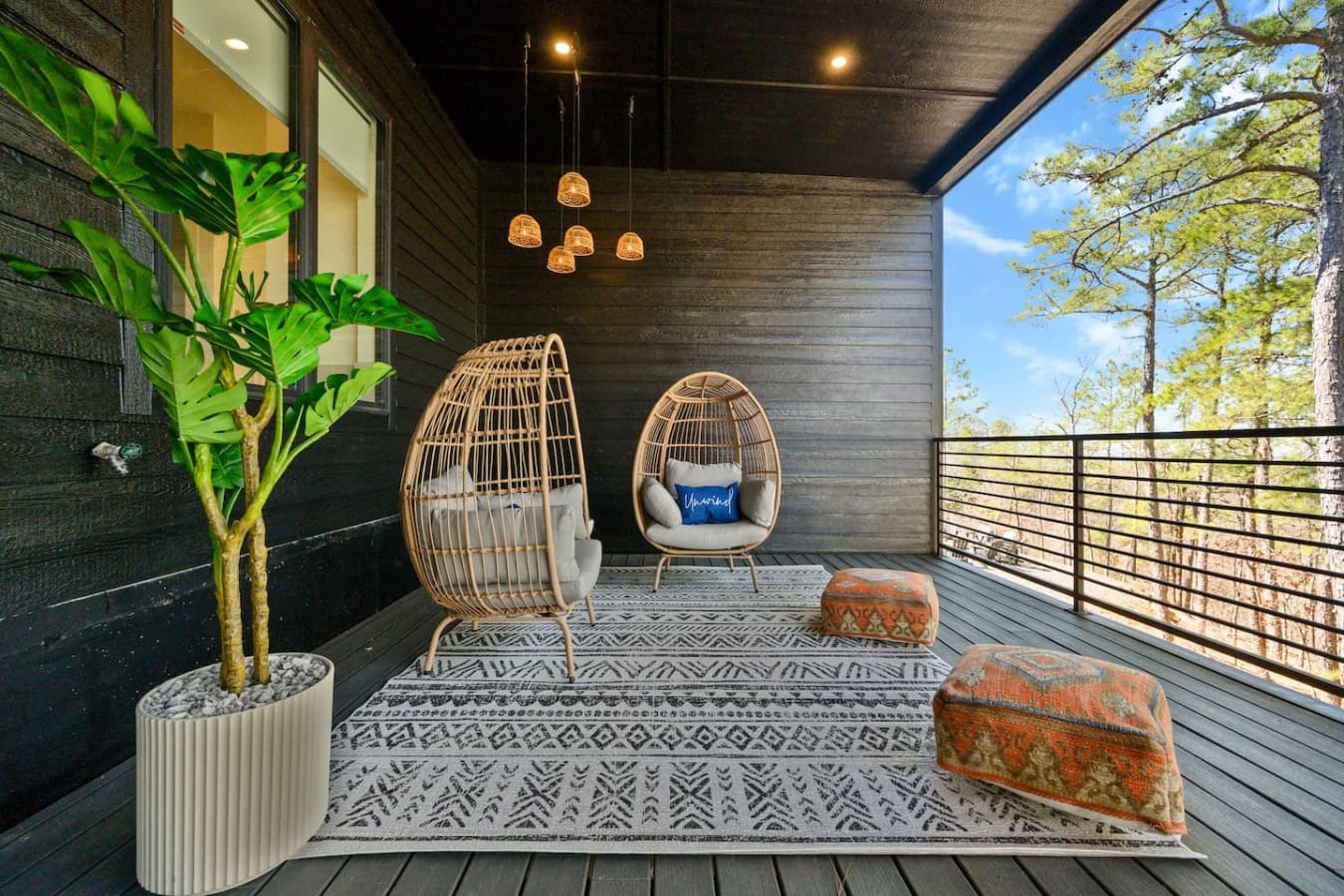This covered deck is basically your own private sanctuary with those hanging egg chairs, woven pendant lights, and views of the treetops—the kind of space that makes you want to skip all your plans and just hang out here for the entire trip.