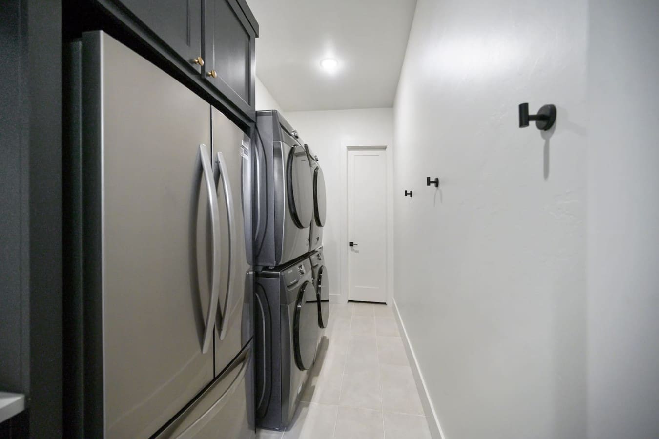 This spotless laundry room with its sleek stacked washer and dryer under custom cabinetry is basically the kind of setup that makes you actually want to tackle laundry day.