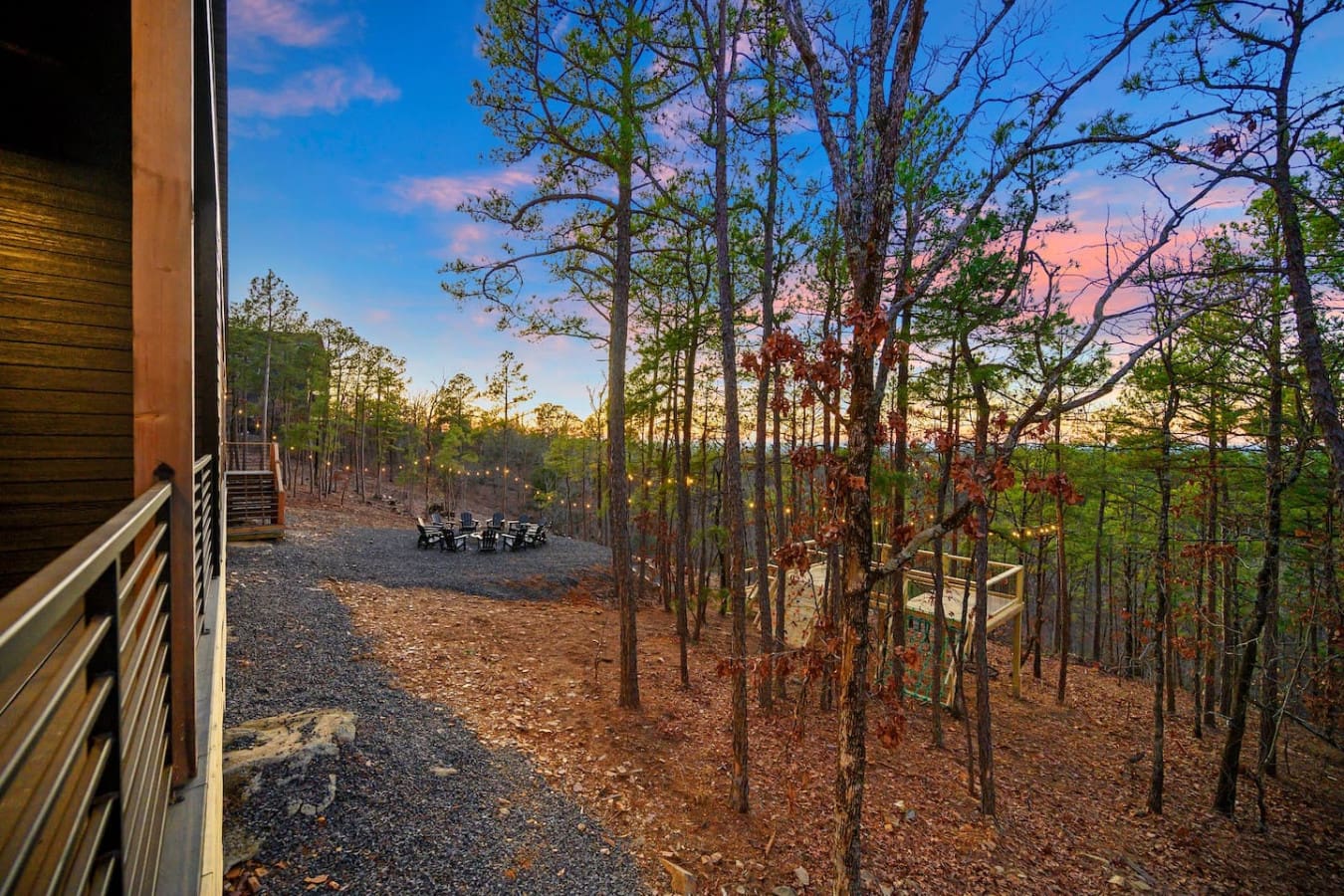 Watching the sky turn pink and purple over an endless forest of tall pines while you're perched on a deck with twinkling lights and cozy seating basically feels like having your own private treehouse view of the world.