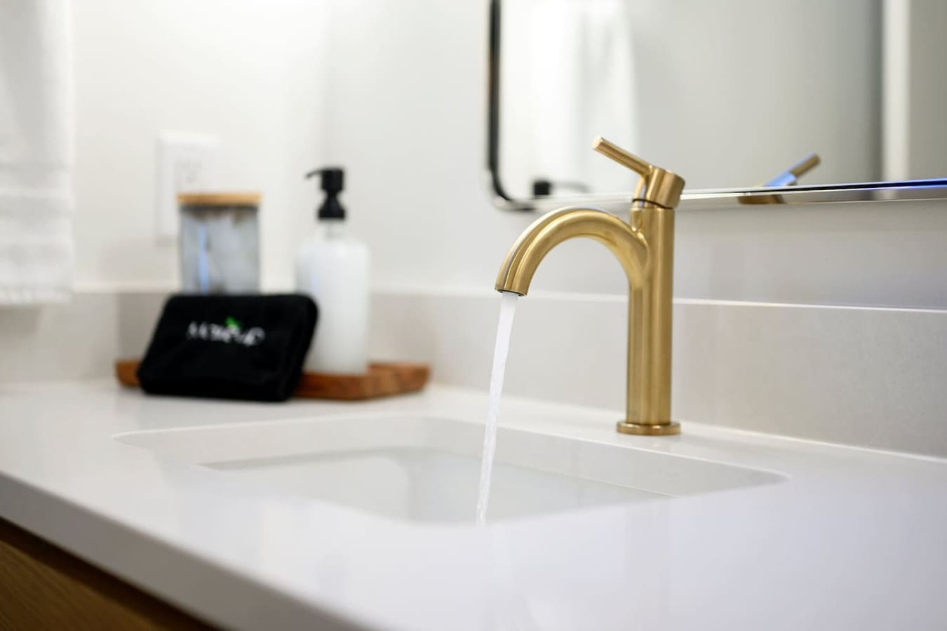 This sleek gold faucet flowing water into a pristine white sink is basically the kind of bathroom detail that makes you feel like you're staying somewhere that sweated all the little things.