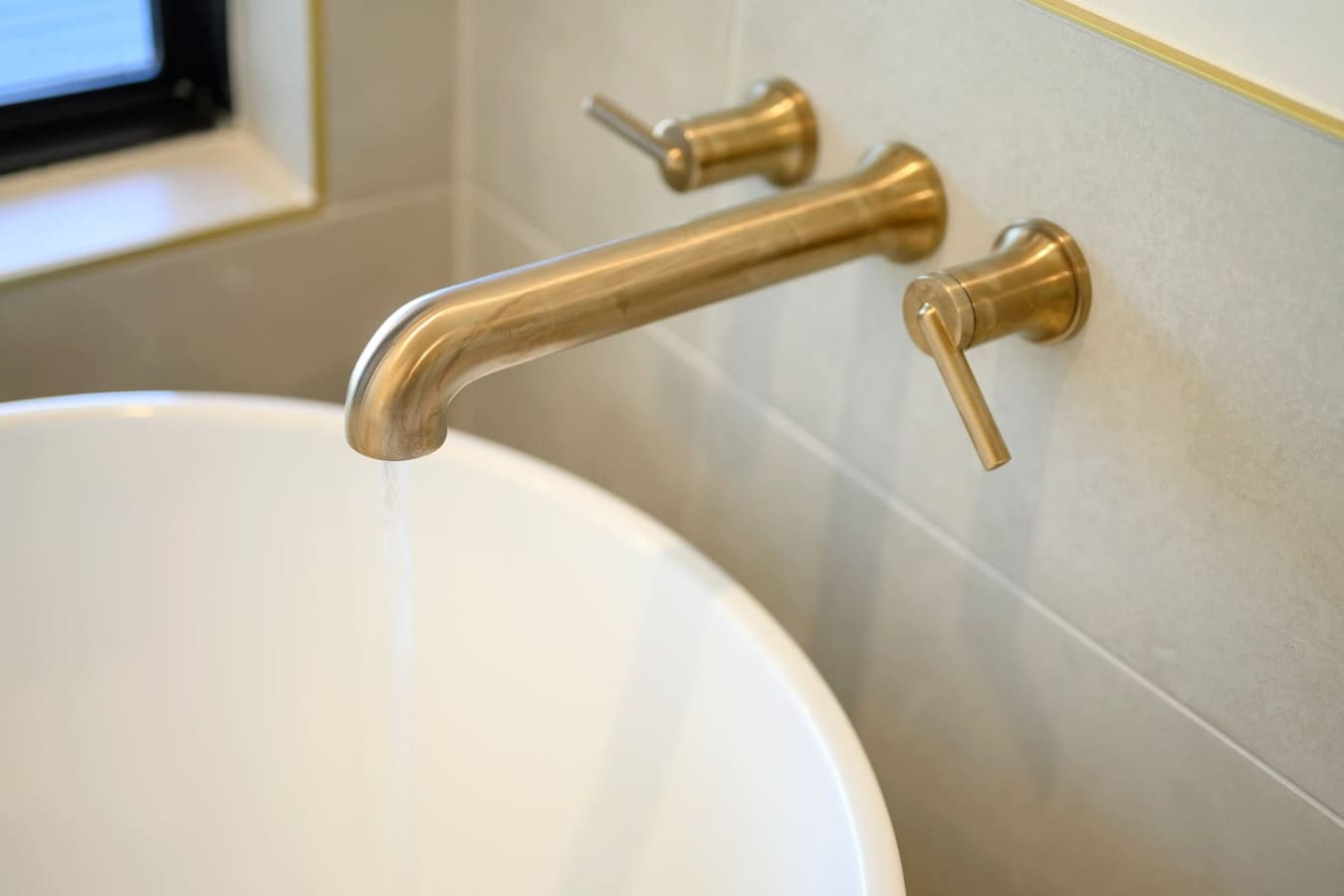 These sleek brass wall-mounted fixtures with that elegant curved spout are basically the kind of bathroom detail that makes you feel fancy every time you wash your hands.