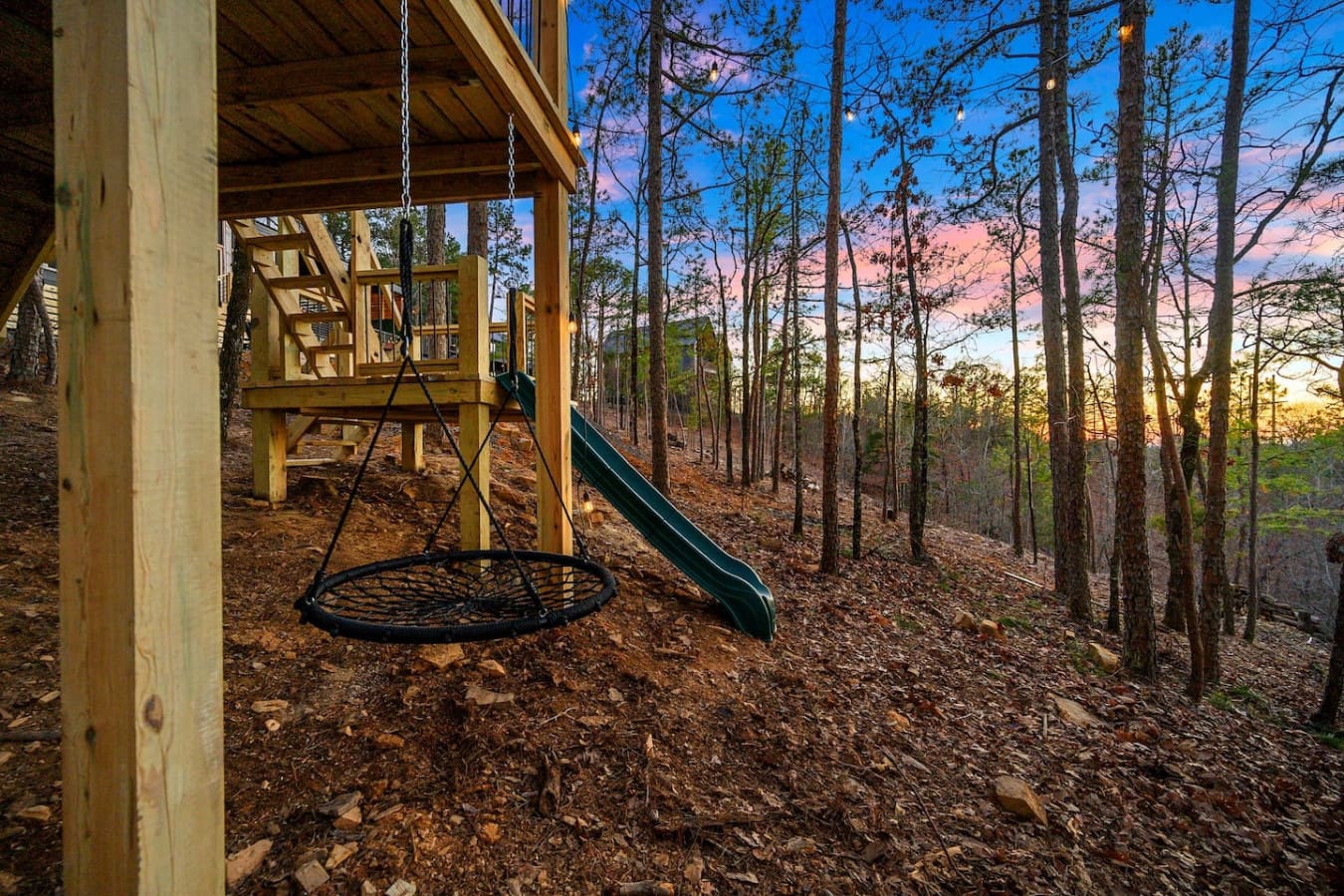 This playground setup nestled among the tall pines is basically the kind of backyard that makes kids forget all about their screens—complete with a swingset, slide, and those gorgeous sunset views painting the sky in the background.