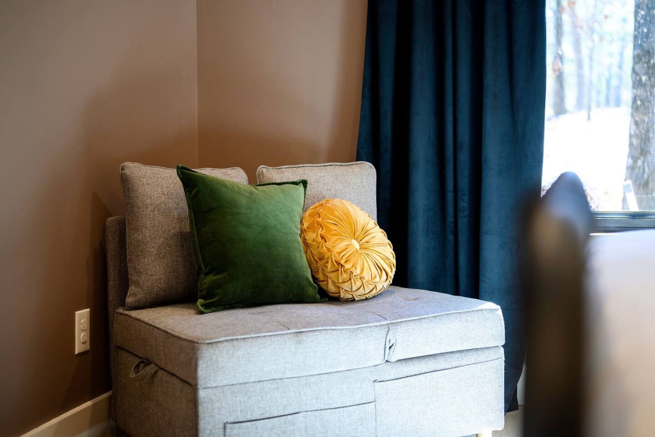 This cozy window nook with its plush seating, jewel-tone pillows, and those dreamy blue curtains basically looks like the perfect spot to curl up with a book and watch the day unfold outside.