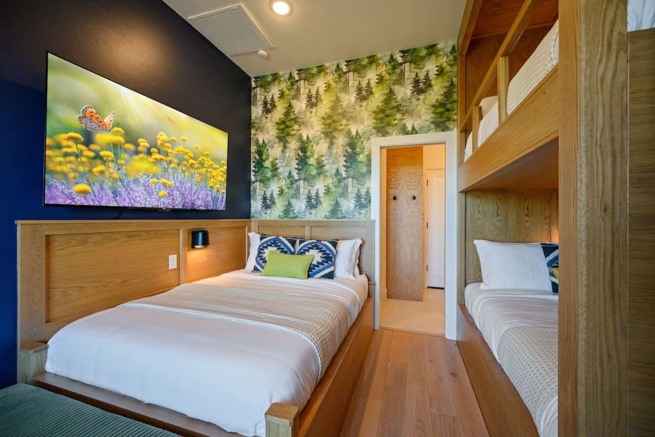 This cozy bedroom setup with its warm wood built-ins, forest wallpaper, and twin beds tucked into alcoves basically feels like sleeping in your own private treehouse cabin.