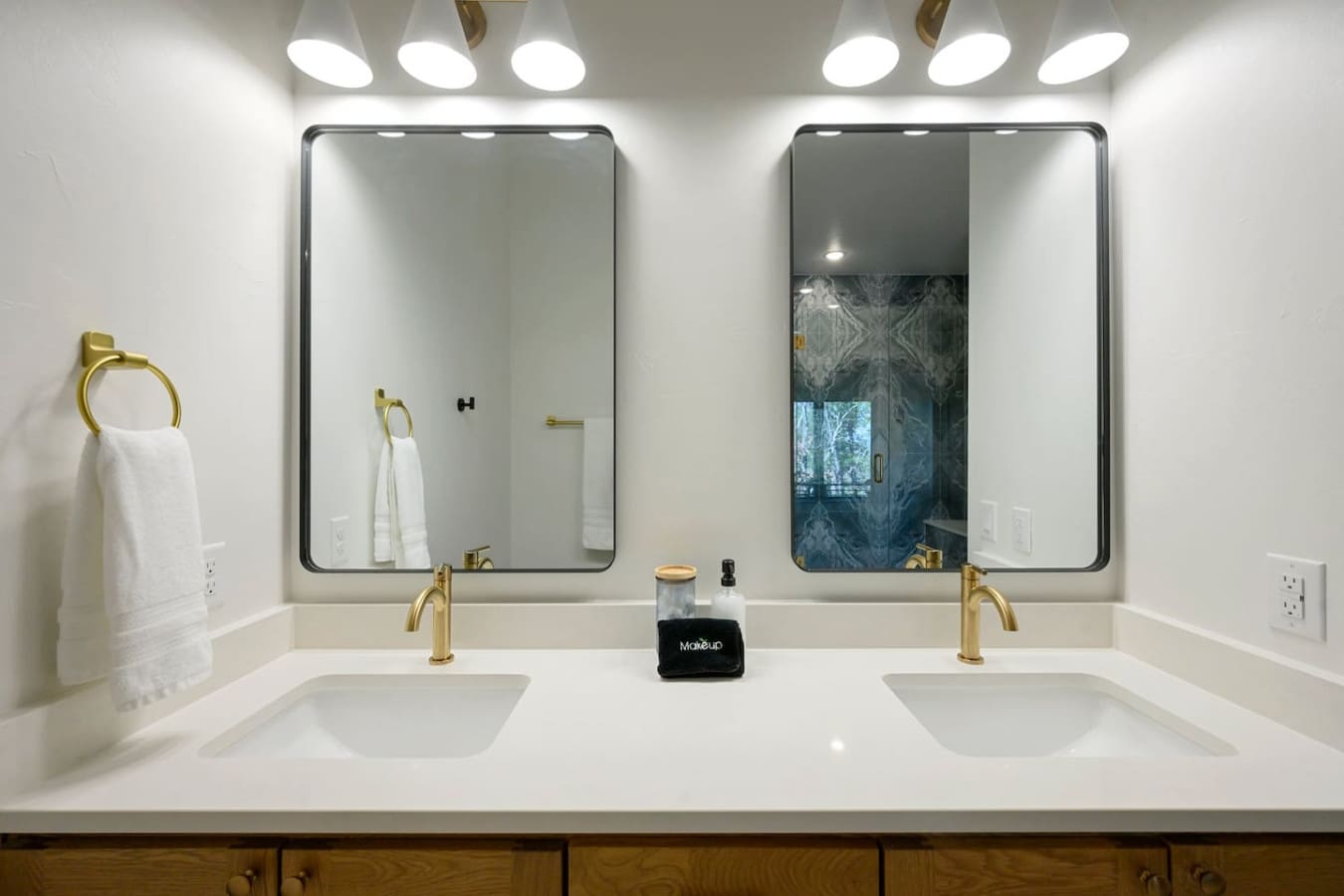 This double vanity is basically the kind of bathroom setup that makes getting ready feel like a spa day, with those perfectly framed mirrors, warm brass fixtures, and bright overhead lighting that somehow makes everything feel effortless.