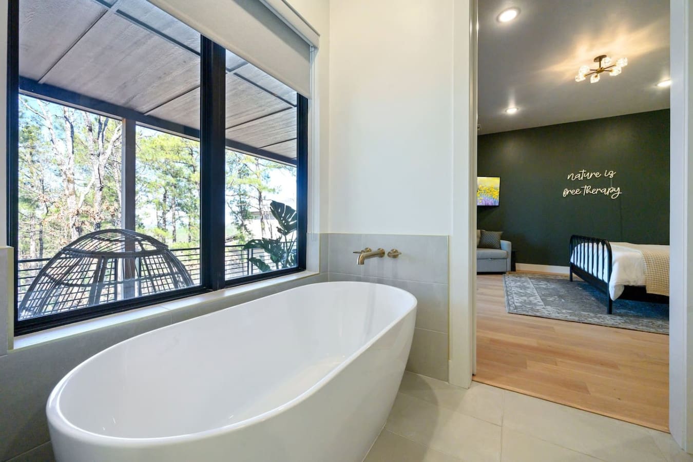 This freestanding tub positioned right by those massive windows is basically the ultimate luxury—soak in the bath while gazing out at the forest and that hanging chair on the deck, because why choose between a spa day and nature therapy when you can have