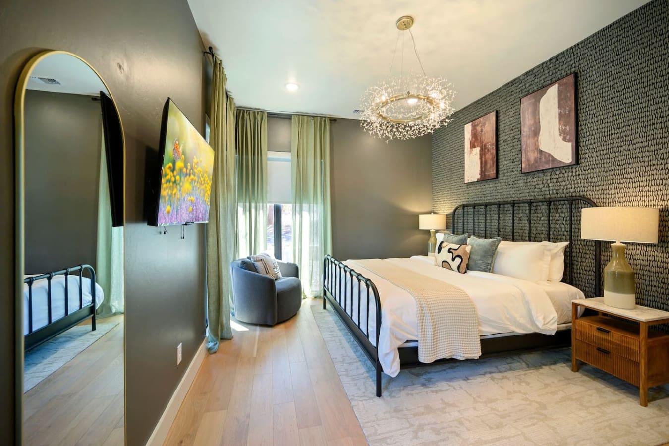 This bedroom is basically the perfect sanctuary with that textured accent wall, elegant black metal bed frame, sparkling pendant chandelier overhead, and all those warm gold accents that somehow make the space feel both modern and incredibly inviting at t