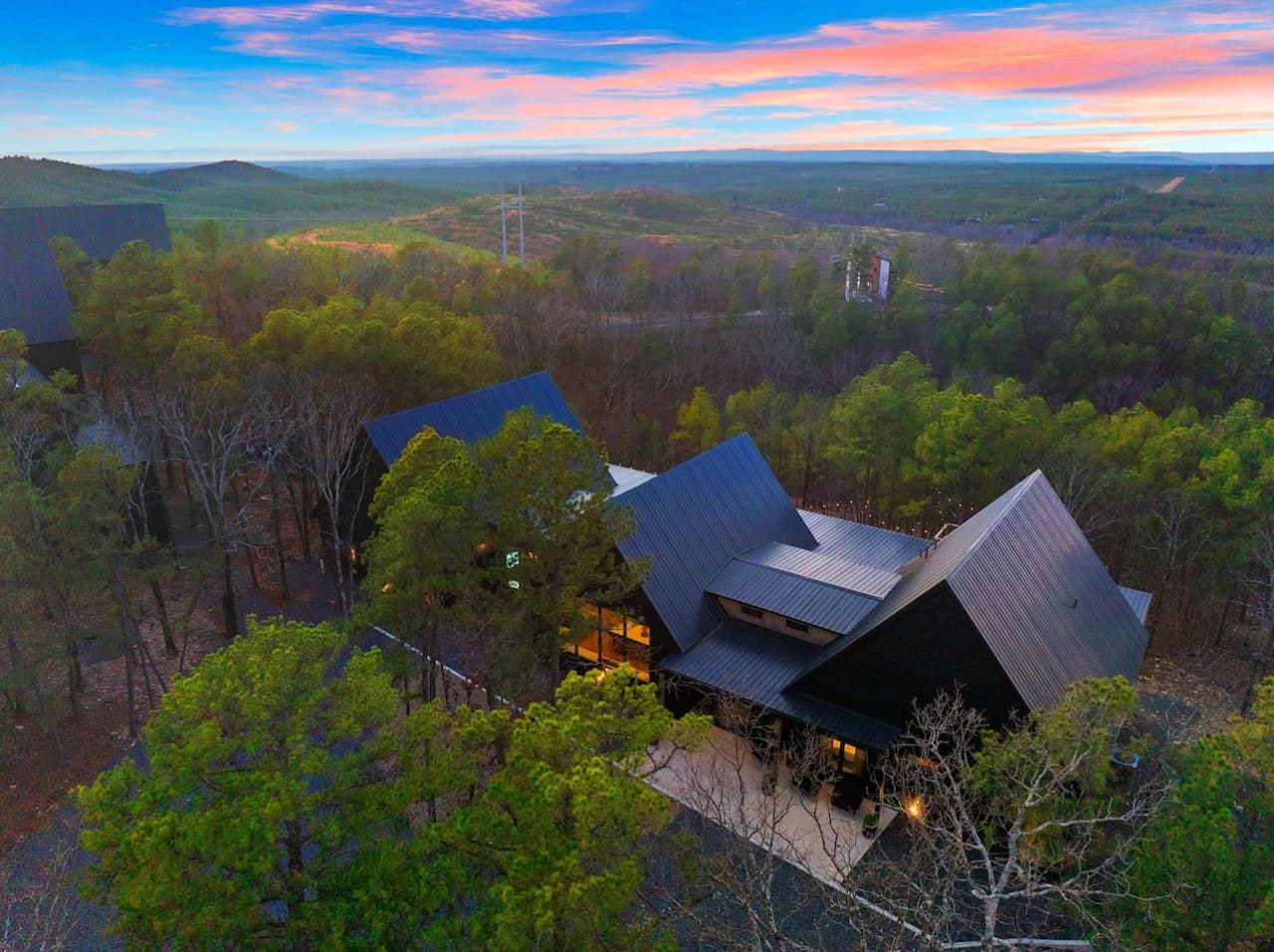 From this architectural gem tucked into the pines, you're basically watching the sunset set the entire sky on fire while the forest stretches endlessly below you—the kind of moment that makes you understand why someone built something this stunning in the
