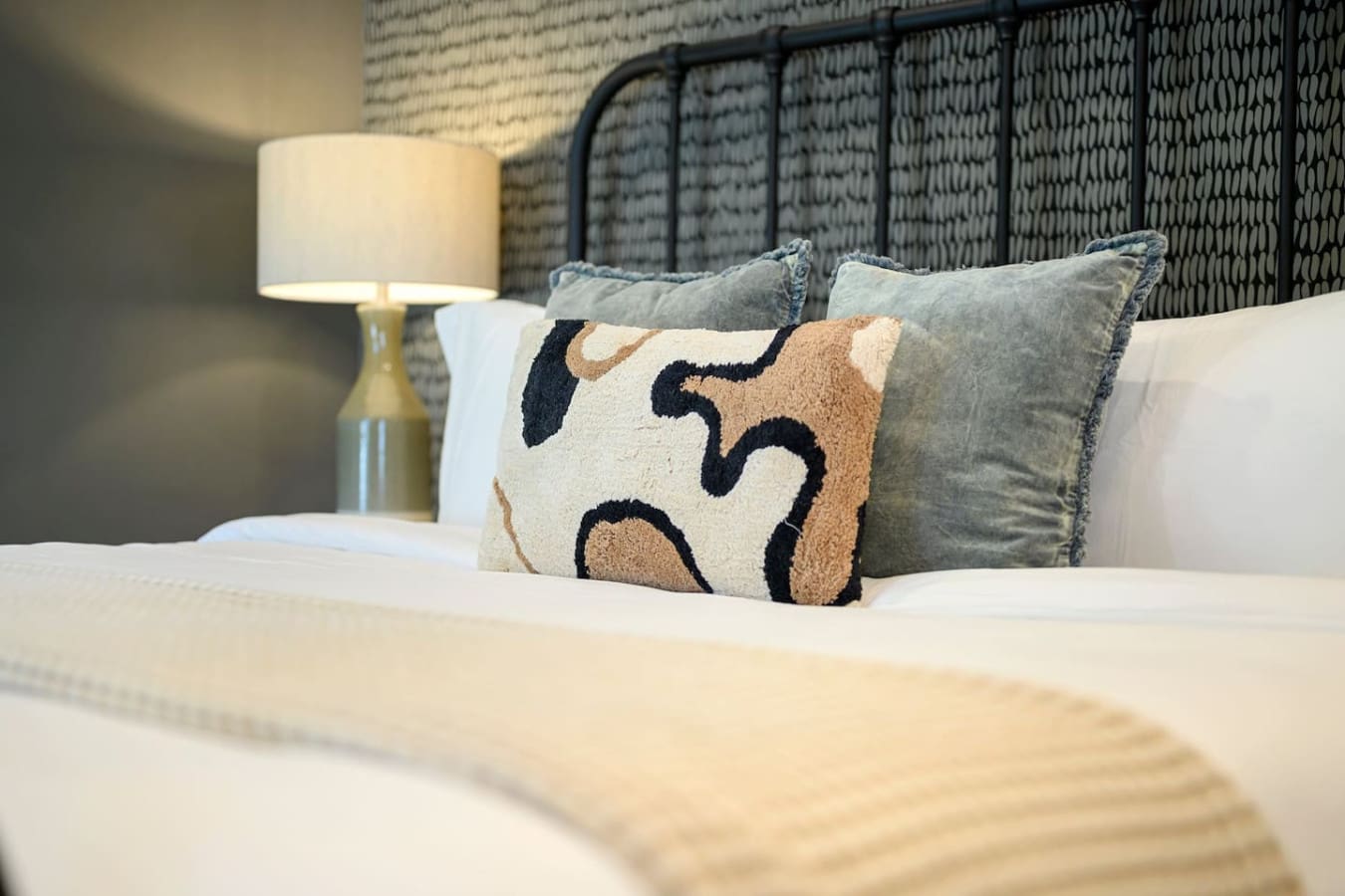 The mix of textured throw pillows and that geometric patterned one in warm neutrals and navy basically gives you all the cozy layering vibes you need to sink into bed and never leave.