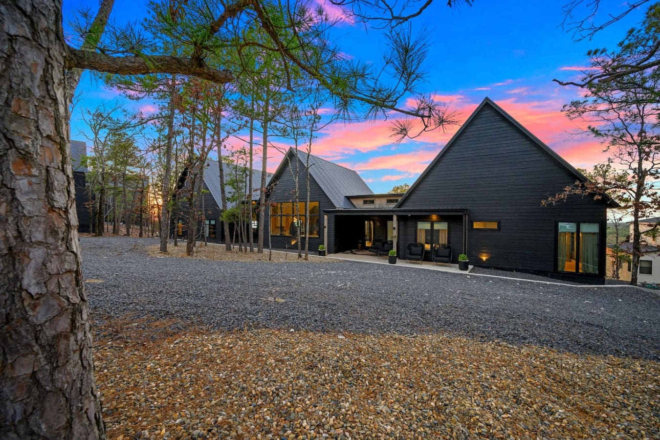 This stunning modern retreat nestled among the pines with its sleek black exterior and dramatic peaked roofs basically looks like the architectural dream you didn't know you needed, especially when you catch it glowing against a sunset sky like this.