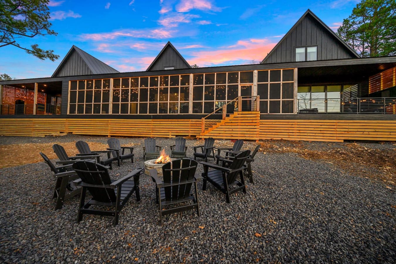 Gather around the fire pit with those comfy Adirondack chairs while the sky lights up in shades of pink and gold—basically the kind of sunset moment that makes you never want to leave this modern forest hideaway.
