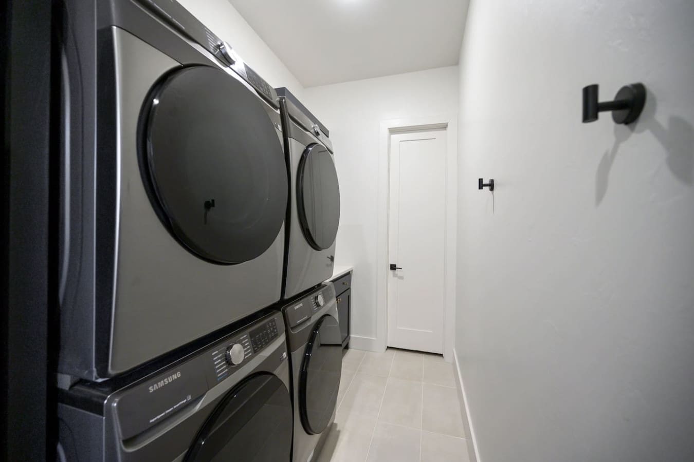 This pristine laundry room with the stacked Samsung washer and dryer is basically the kind of setup that makes doing laundry feel way less like a chore and more like you're actually taking care of yourself.