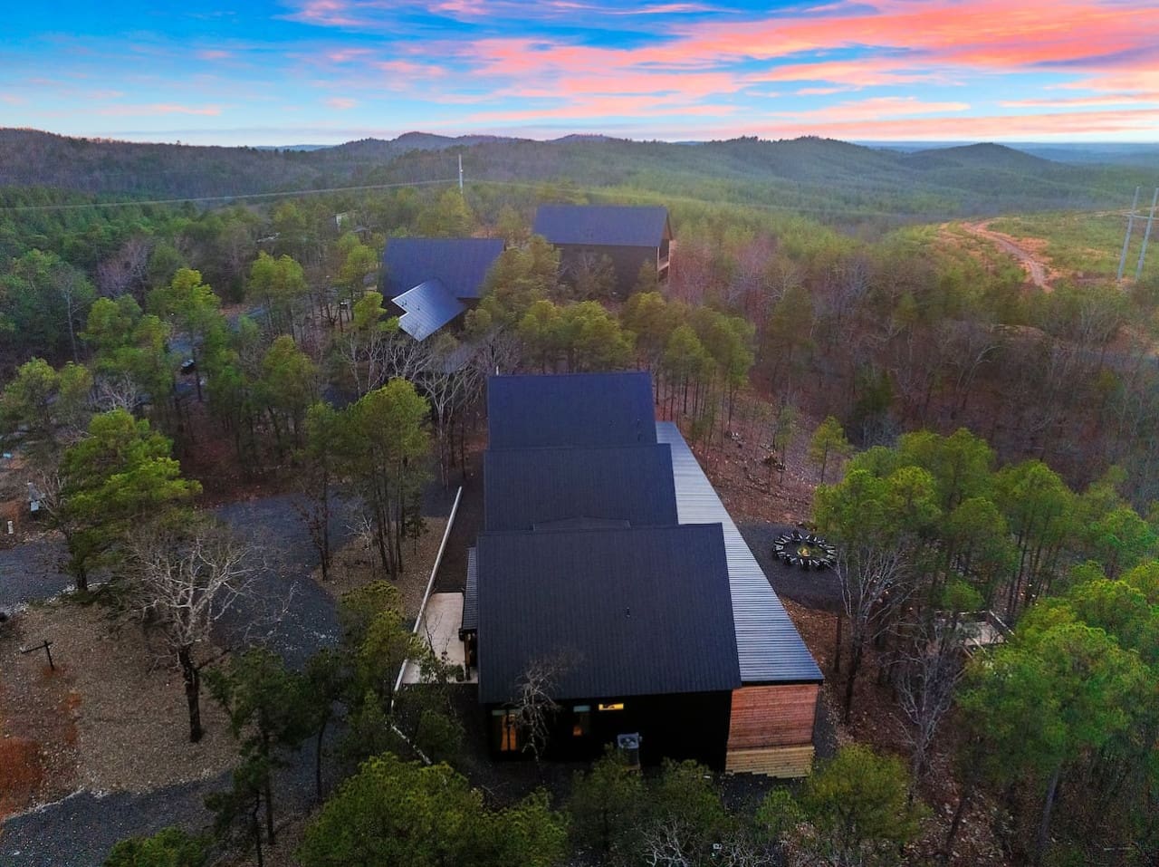 This modern forest hideaway with its dramatic dark roofs and glowing windows basically looks like the ultimate spot to watch that golden-hour sky unfold while you're completely wrapped up in the quiet peace of endless trees and mountains stretching out in