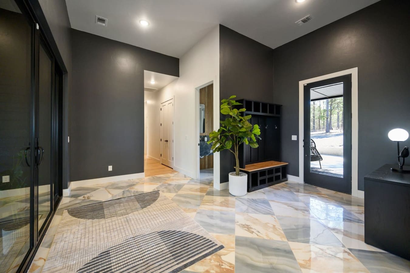 This modern entryway with its moody dark walls, polished marble floors, and that perfectly-placed plant basically says "welcome to something special" before you even step foot inside.