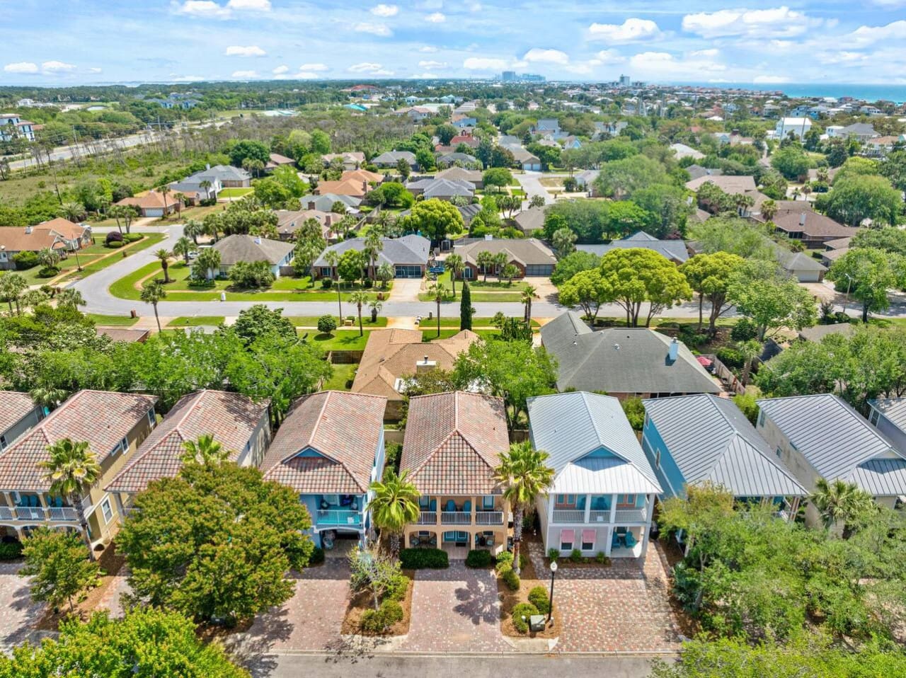 This aerial view is basically your golden ticket to that "best of both worlds" beach vacation—close enough to catch the ocean breeze, far enough to have your own peaceful tree-lined sanctuary, and surrounded by enough colorful roofs to know you've landed
