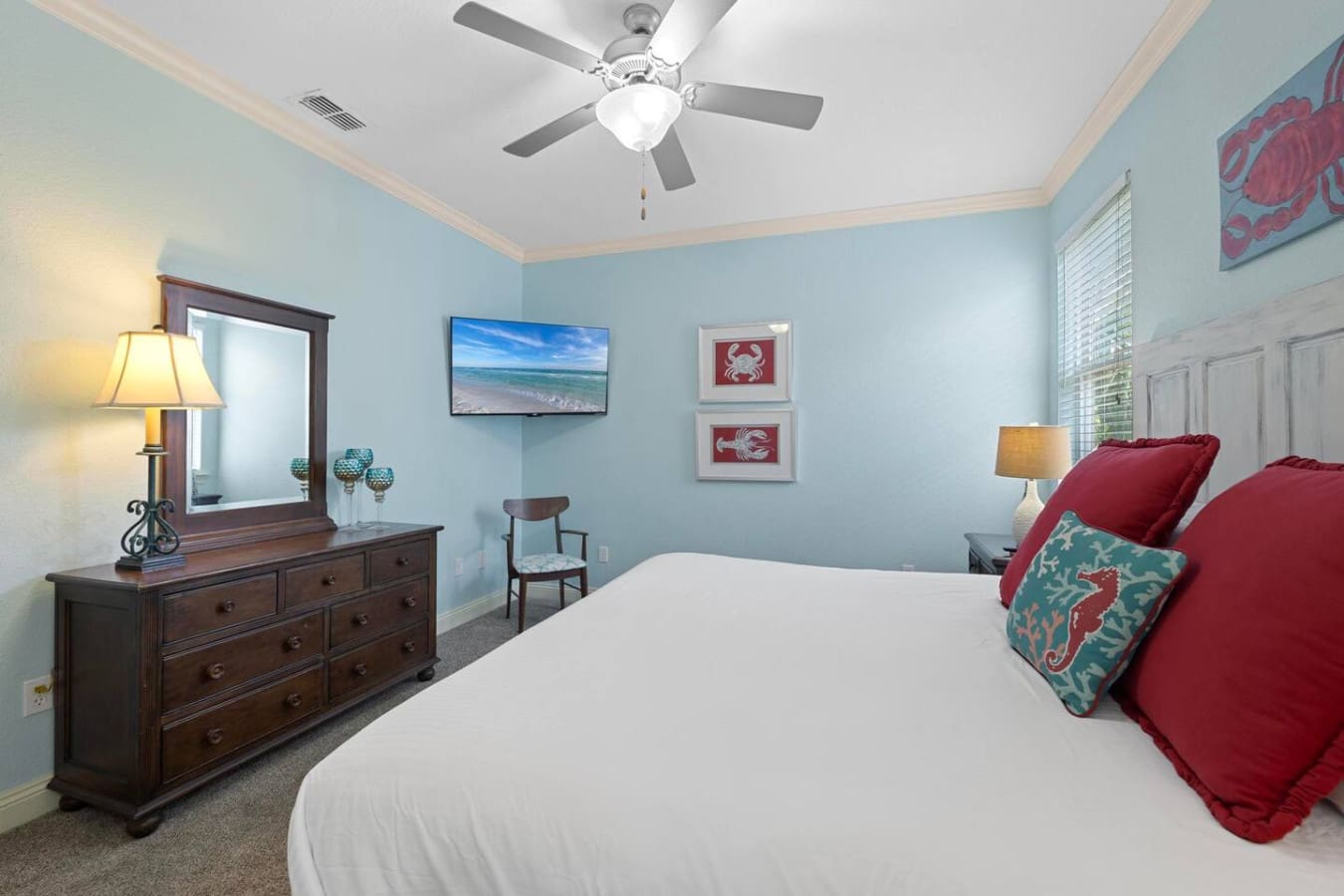 This master bedroom hits that sweet spot where you can practically taste the salt air without leaving your bed, thanks to those beach vibes, cozy red bedding, and the kind of peaceful blue walls that make you forget what day it is.