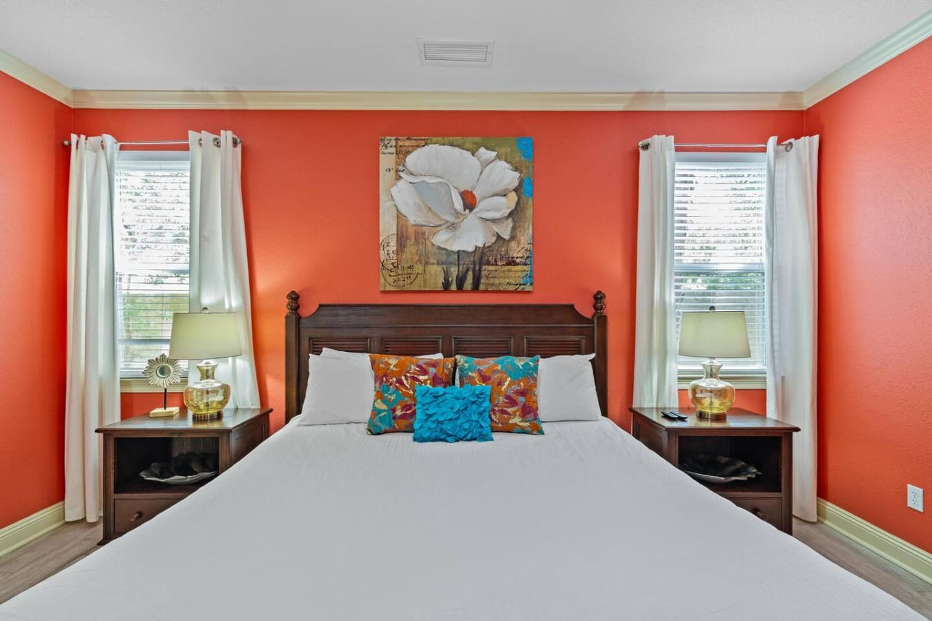 The master bedroom's vibrant coral walls and colorful accent pillows basically wrap you in pure vacation energy the moment you walk in—it's the kind of space that makes waking up feel like part of the adventure.