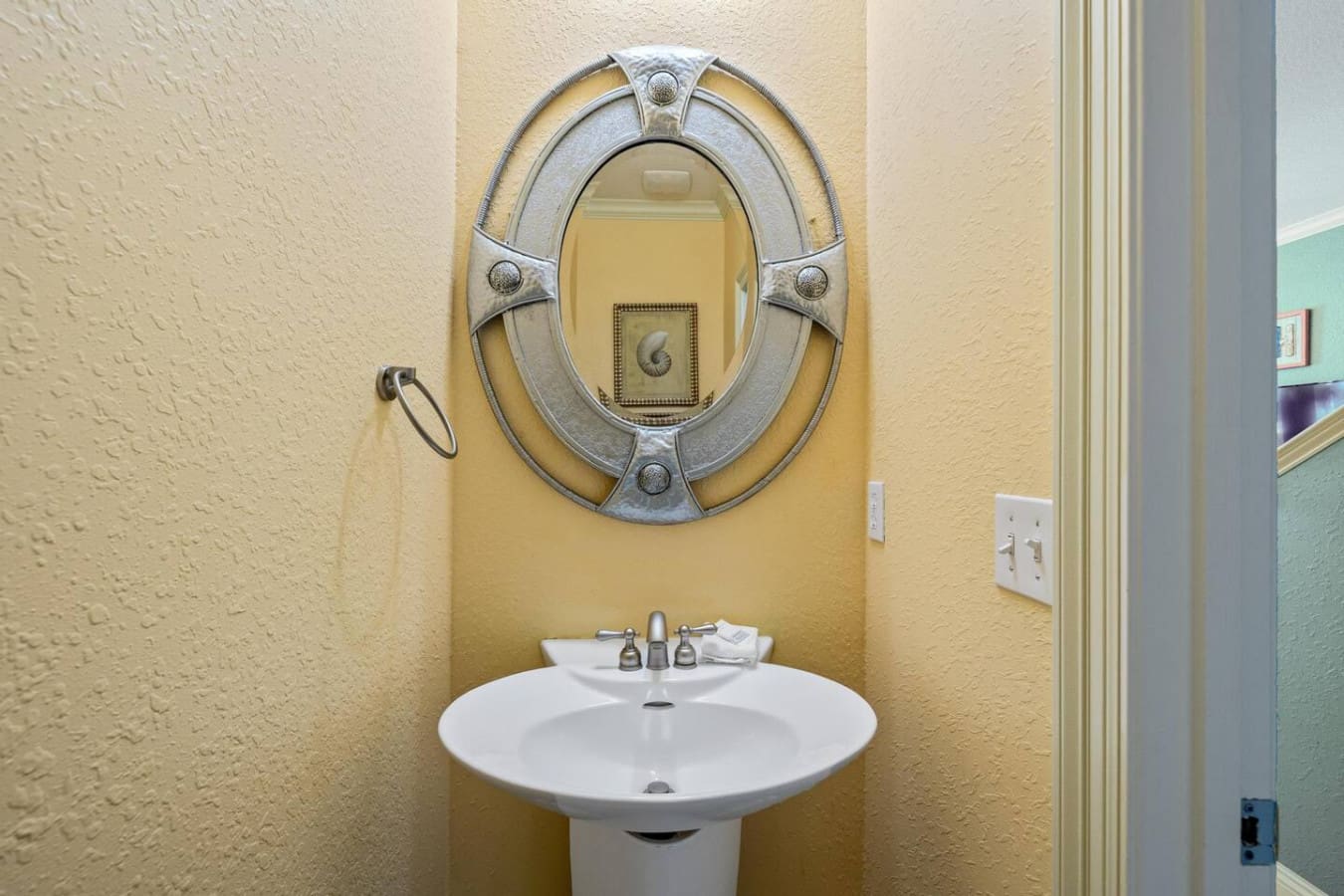 This charming powder room with its cheerful yellow walls and ornate silver-framed mirror is basically the perfect blend of elegant and whimsical—proof that even the smallest spaces in this place deserve their moment to shine.