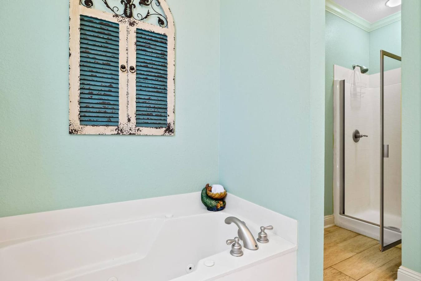 This spa-like master bathroom with its serene seafoam walls, soaking tub, and that adorable distressed shutter art basically gives you permission to slow down and soak in the whole vacation vibe.