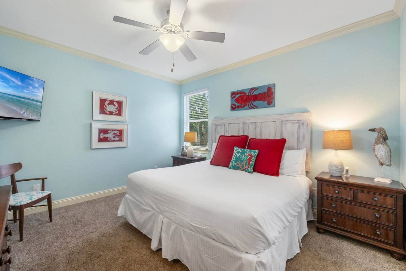 This mint-green bedroom with its crisp white bedding, cheerful red accents, and those nautical touches is basically your personal seaside retreat before you even step foot on the sand.