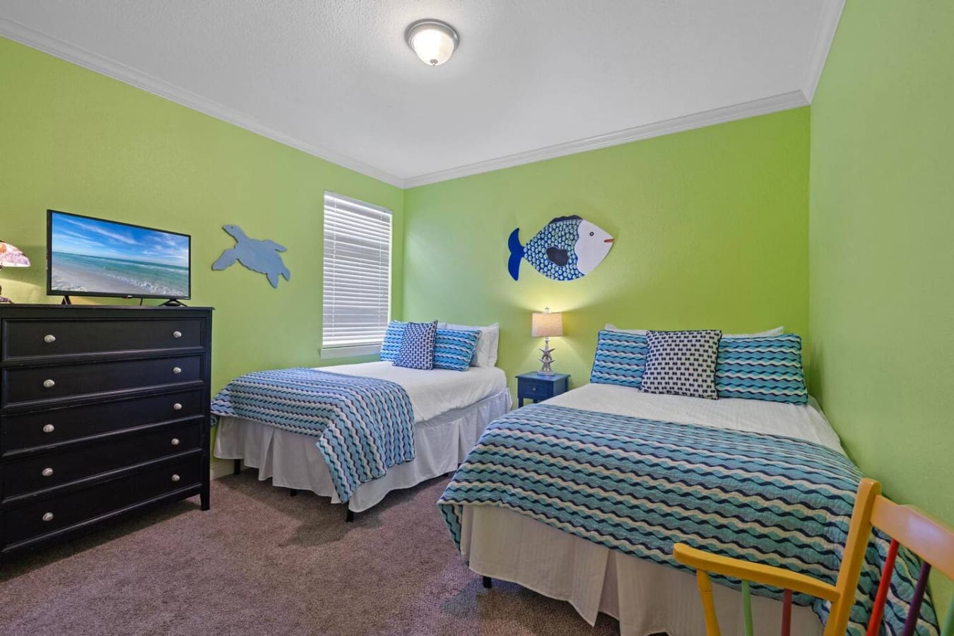 This ocean-themed kids' bedroom with its lime-green walls, coordinating fish art, and perfectly matched bedding is basically saying "welcome to your own underwater adventure" the moment you walk through the door.