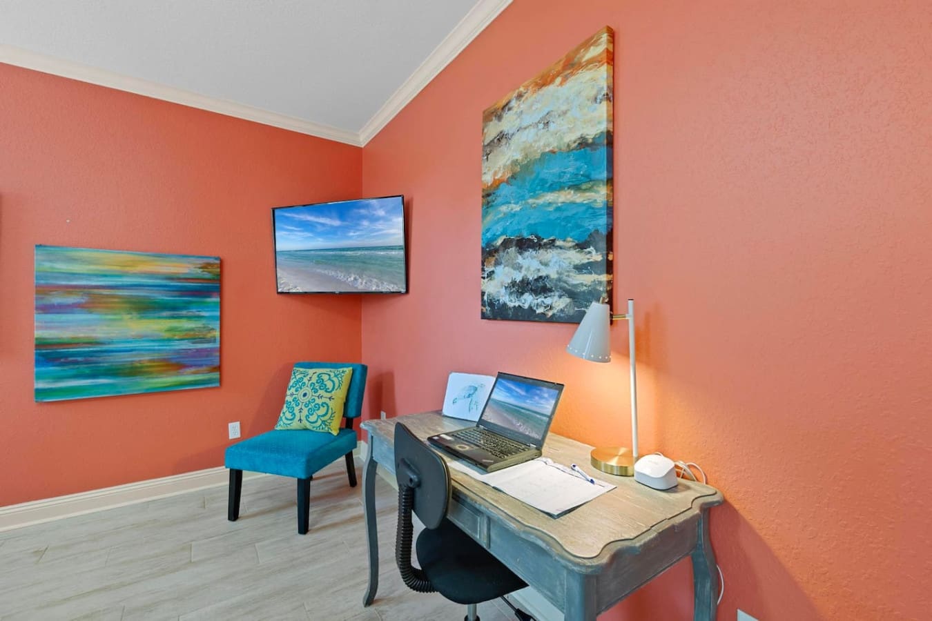 This coral office nook basically proves that your workspace doesn't have to be boring—between those ocean-inspired artworks, a desk with actual personality, and walls that practically whisper "you can totally work from here," it's the kind of setup that m