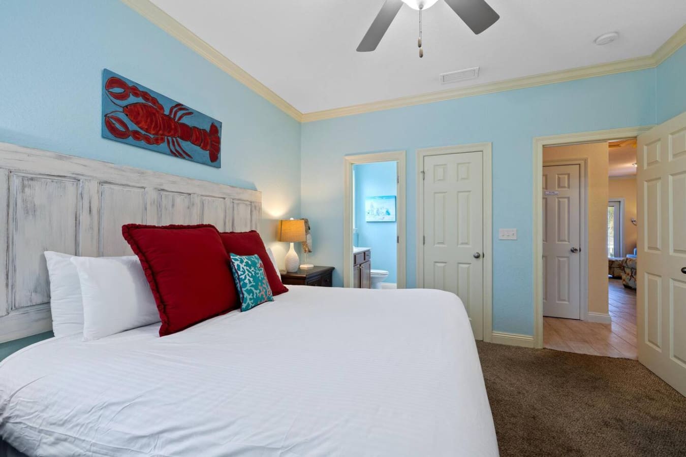 This master bedroom nails the whole "coastal calm meets playful personality" thing with its serene blue walls, that whitewashed headboard, and those bold red pillows that basically dare you to not feel relaxed.