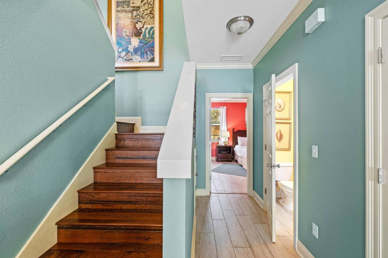 The turquoise hallway with its warm wood stairs and perfectly placed doors is basically the spine of this place—keeping everything organized, connected, and impossibly cute all at the same time.