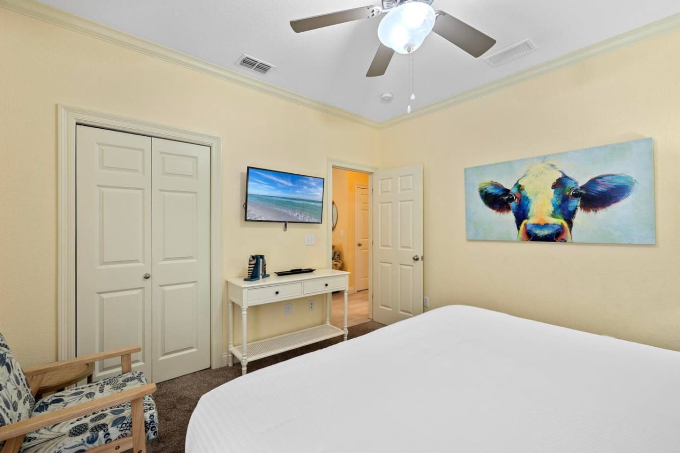 This bright, airy bedroom with its colorful cow art and cute desk setup is basically the perfect blend of relaxation and personality—complete with that ceiling fan keeping things cool while you plan your beach day.