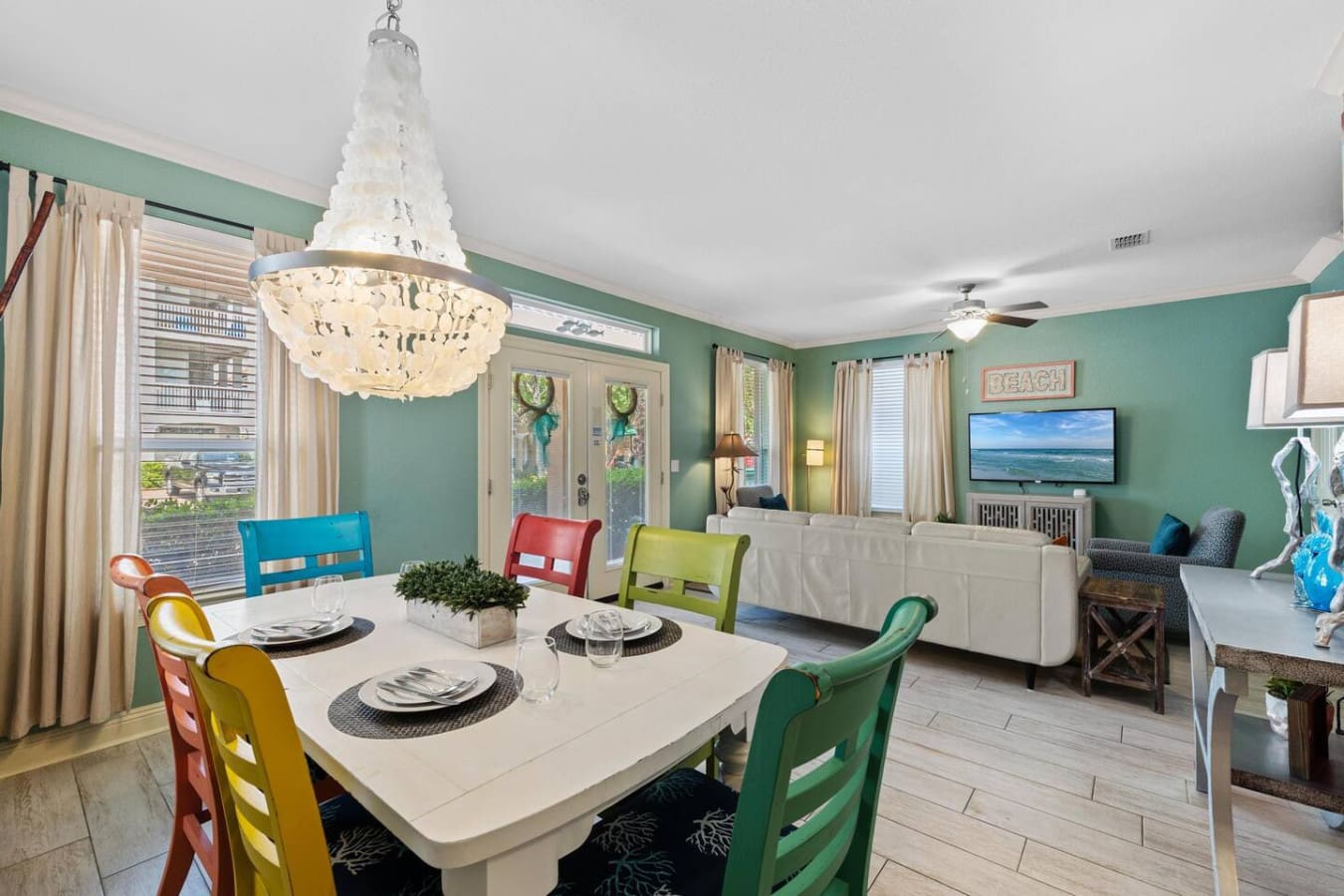 This dining area is basically screaming "let's make this meal memorable"—between those vibrant ladder-back chairs in every color of the rainbow, that gorgeous beaded chandelier, and those mint-green walls, even breakfast feels like a special occasion.