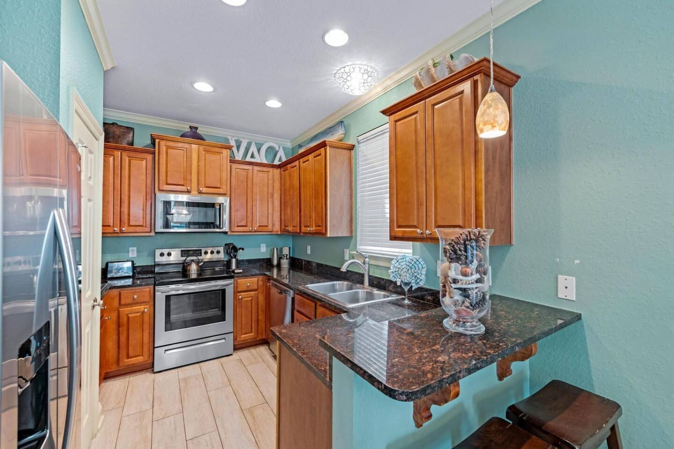 This kitchen basically nails the whole "cooking feels like a vacation" vibe with its warm wood cabinets, sparkling granite counters, and those turquoise walls that make even the mundane task of chopping vegetables feel like you're part of something specia
