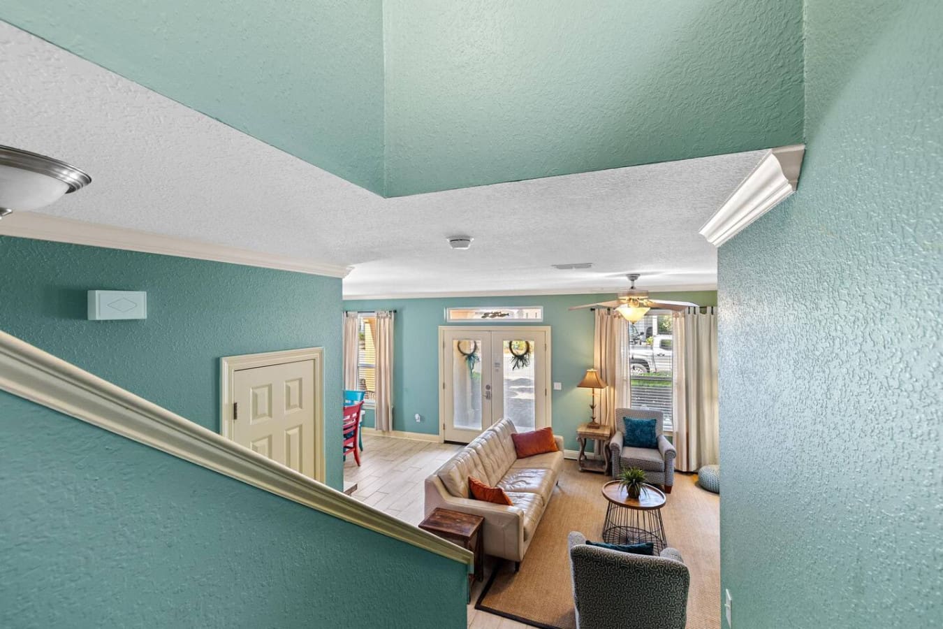 This bright, open living room with its turquoise walls, soaring ceilings, and those perfectly positioned glass doors basically gives you the best of both worlds—cozy indoor hangouts and easy access to all your beach day adventures.