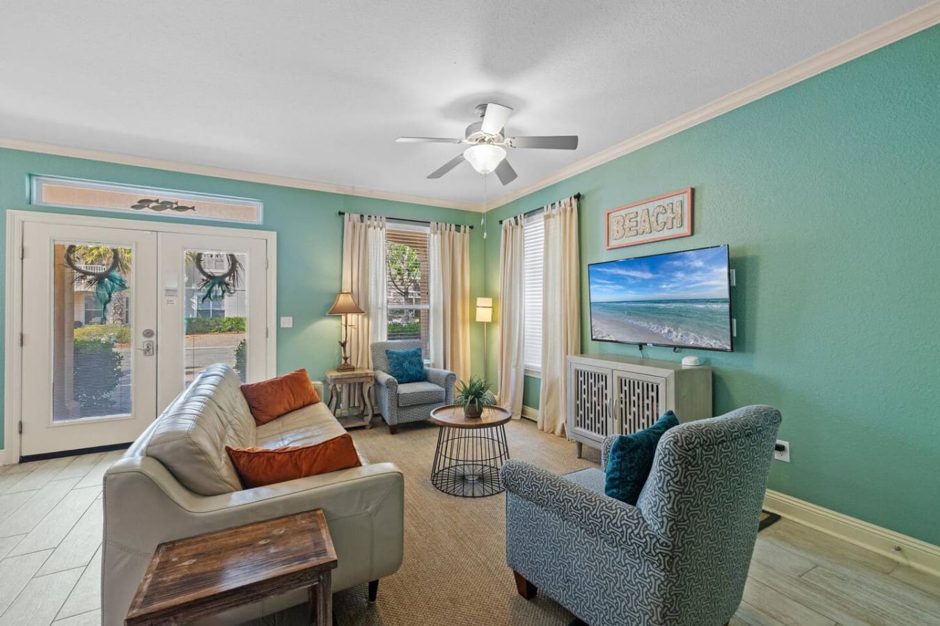 This living room is basically the definition of "come hang out"—with those turquoise walls, natural light pouring in from every angle, and enough comfortable seating to gather the whole crew around that perfect little coffee table.