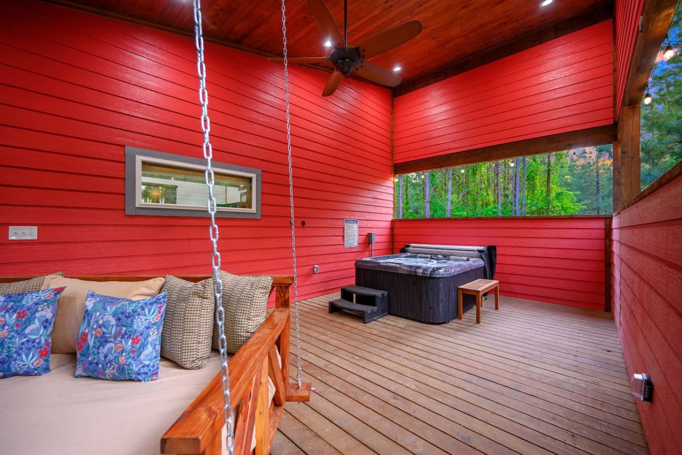 This red cabin's got serious personality—part relaxation retreat with that swinging bed, part fun hangout with the hot tub right there, all wrapped up in those bold barn-red walls that somehow feel both cozy and adventurous at the same time.