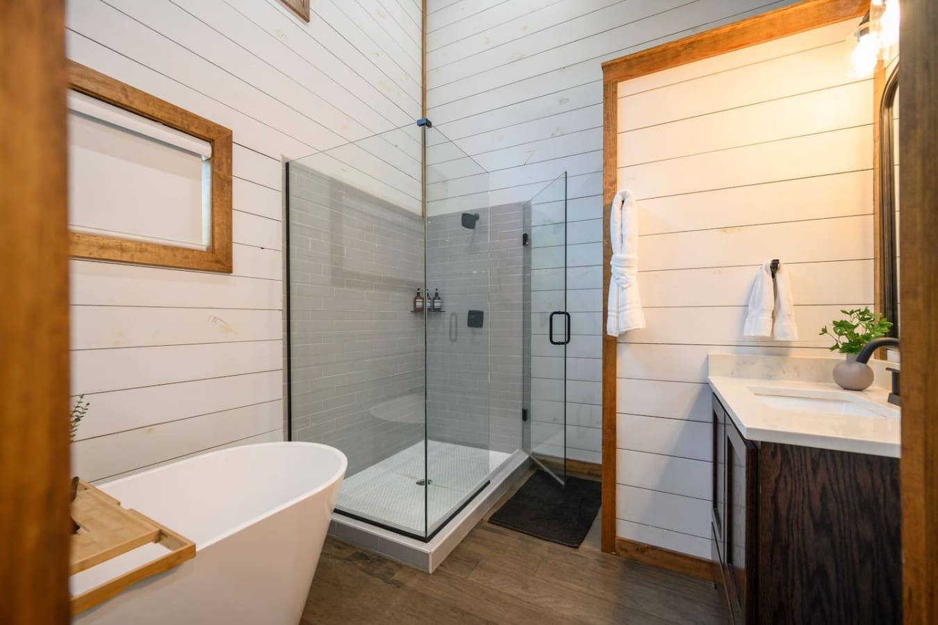This bathroom somehow manages to feel like a spa retreat and a rustic cabin at the same time—all shiplap walls, natural wood frames, a soaking tub, and a walk-in shower that'll make your morning routine feel way less like a chore.