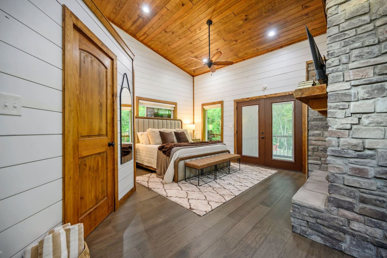 This master suite basically has it all—a stone fireplace, those killer forest views through glass doors, and a bed so inviting that checking out the rest of the cabin might actually feel like a chore.