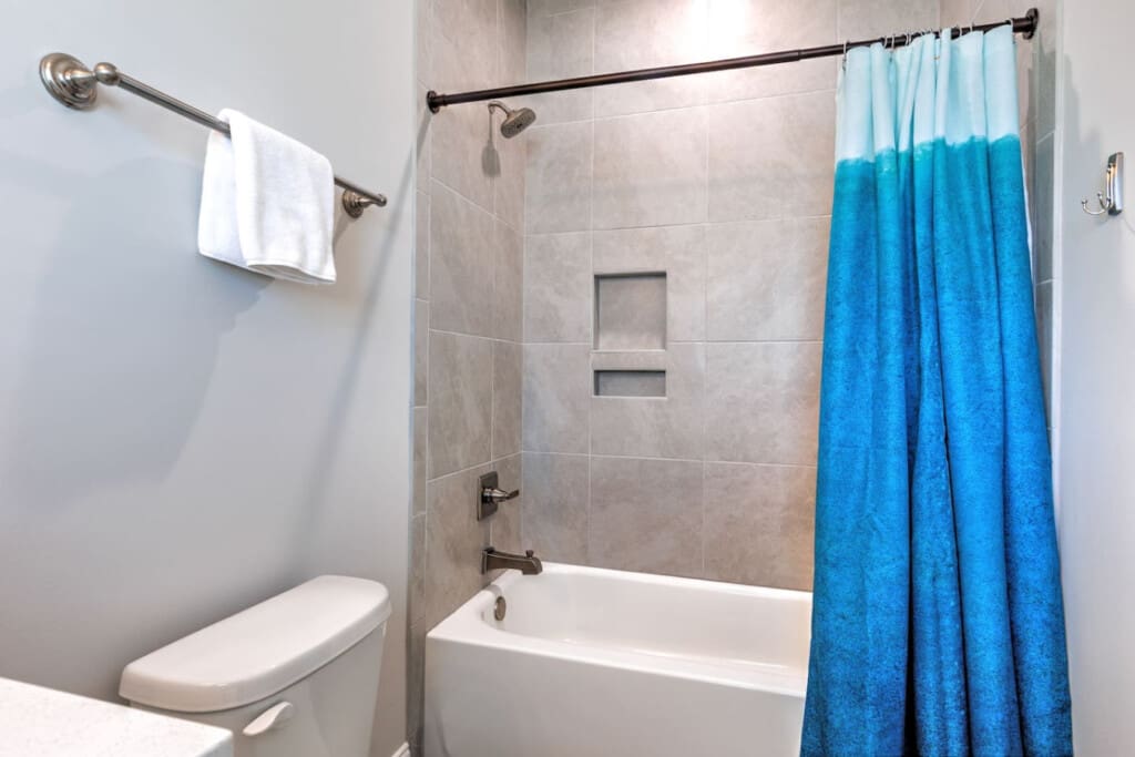 This clean, functional bathroom has everything you need to get ready, from the spacious vanity to the tub-shower combo and that bright blue ombre curtain that adds a fun pop of color to the space.