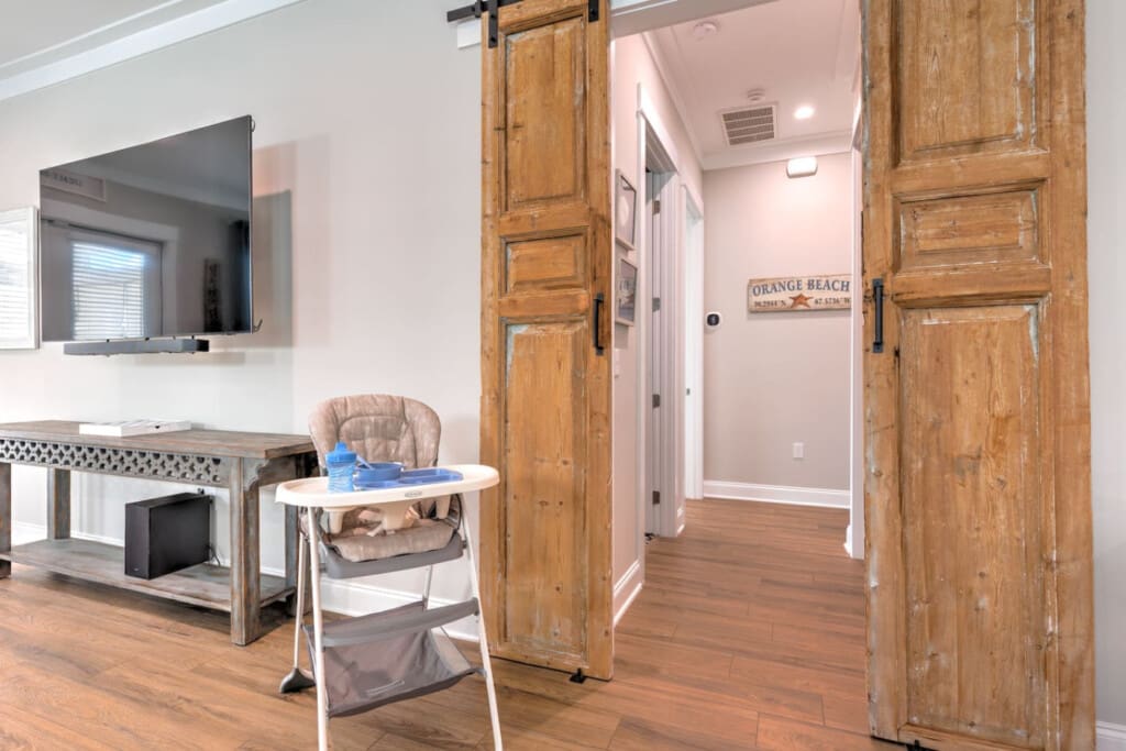 This open-concept living area is giving major beach house vibes with those beautiful rustic barn doors, tons of natural light, and plenty of room to spread out and relax after a day at the beach.