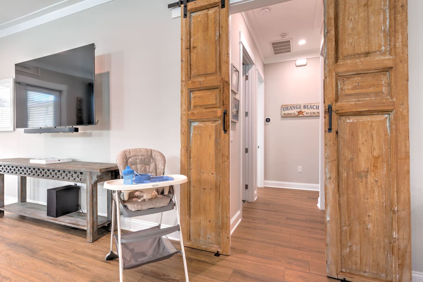 This open-concept living area is giving major beach house vibes with those beautiful rustic barn doors, tons of natural light, and plenty of room to spread out and relax after a day at the beach.